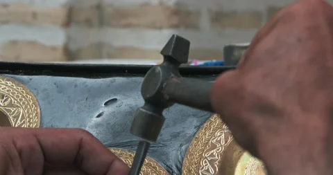 A master embosser creates a pattern on a copper plate using ancient technologies Stock Footage 264138537