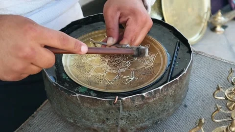 The master engraves patterns on a metal plate. Close-up, handmade, slow motion Video stock 243481563