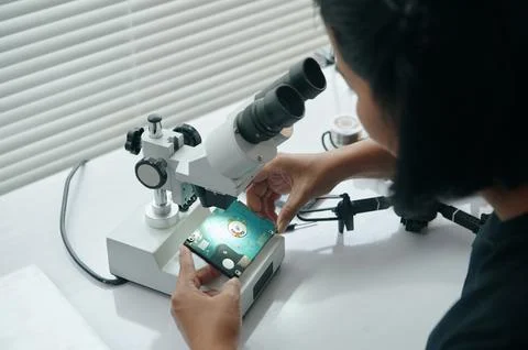 Master Examining Disk Under Microscope Foto stock