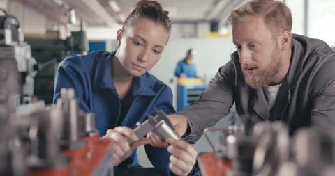 Master explaining apprentice how to measure drill parts with caliper Video stock 254680370