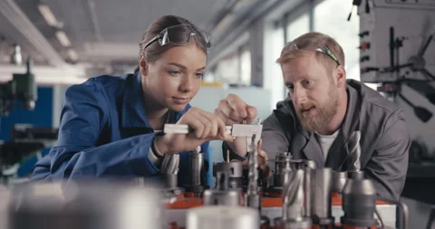 Master explaining apprentice how to measure drill parts with caliper Stock Footage 254680859