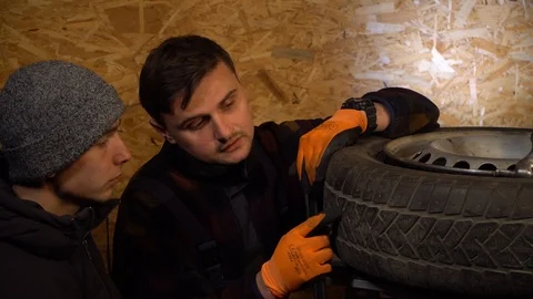 The master explains to the client why it is necessary to change the tire Stock Footage 126527924