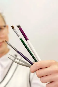 The master of eyebrows holds in his hands brushes for coloring hairs on a lig Foto stock