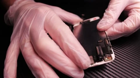 The master fixes the phone, using tools. Close up hands, black table, diy Video stock 261407059