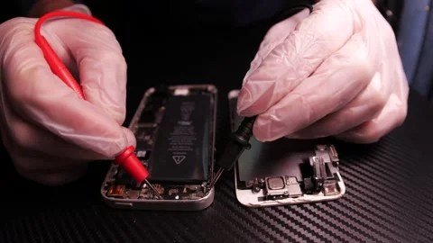 The master fixes the phone, using tools. Close up hands, black table, diy Video stock 261408375