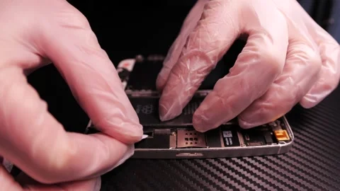 The master fixes the phone, using tools. Close up hands, black table, diy Video stock 261409070