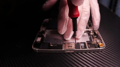 The master fixes the phone, using tools. Close up hands, black table, diy Video stock 261409389