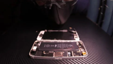 The master fixes the phone, using tools. Close up hands, black table, diy Video stock 261410076