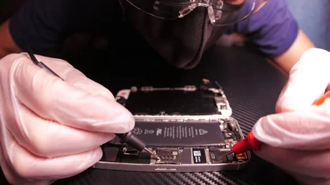 The master fixes the phone, using tools. Close up hands, black table, diy Video stock 261410832