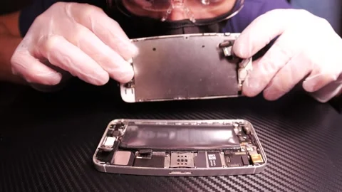 The master fixes the phone, using tools. Close up hands, black table, diy Video stock 261411358