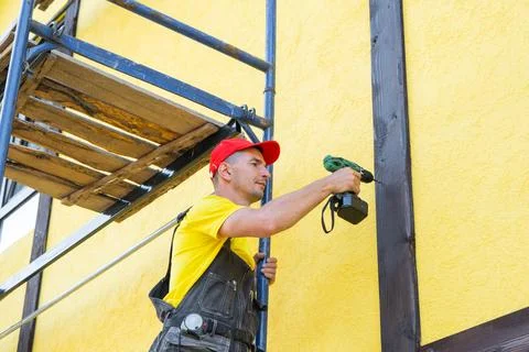 Master fixes timber element to house wall, half-timber (fachwerk) design, d.. Stock Photos