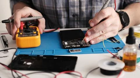 Master Fixing Microchip Of Broken Smartphone, Using Digital Mult Stock Photos