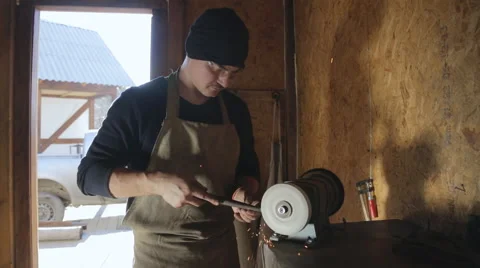 Master gently sharpens metal piece on a grinding machine Stock Footage 64335455