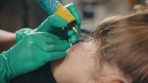 Master in gloves beats tattoo on neck client with machine according to sketch. Stock Footage 219549471