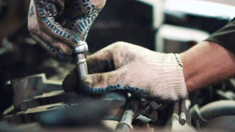 Master in gloves unscrews the bolt with a silver key close up Stock Footage 153172110