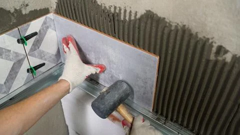 The master glues ceramic tiles on the wall in the bathroom. Adjustment of cer Stock Photos