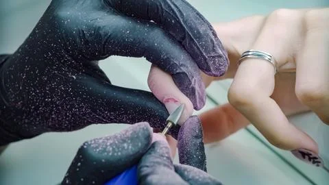 Master grinds nails using electric cuticle rejpger Stock-Fotos