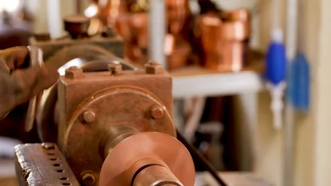 The master grinds a part of a copper product using a lathe Stock Footage 124471164