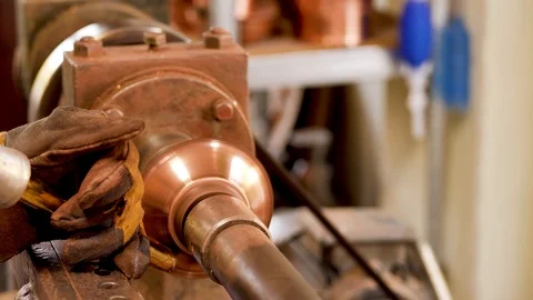 The master grinds a part of a copper product using a lathe Stock Footage 124471459