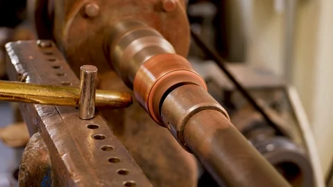 The master grinds a part of a copper product using a lathe Stock-Footage 124575356