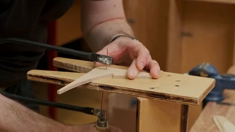 Master hands cut brown airplane model wing with jigsaw slow Stock Footage 127377084