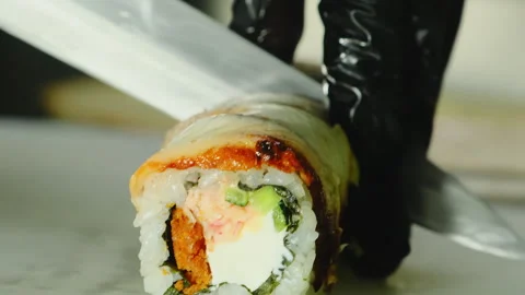 Master hands cut sushi roll with smoked eel into slices on plate Stock Footage 324805380