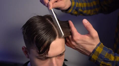 Master hands hold instruments and perform hairstyle for guy Stock Footage 132893870