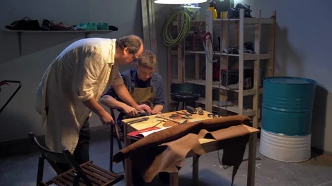 Master helps man to make a shoe in a workshop Stock Footage 126721399