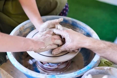 The master helps the student to make a pot of clay. Pottery wheel Foto stock
