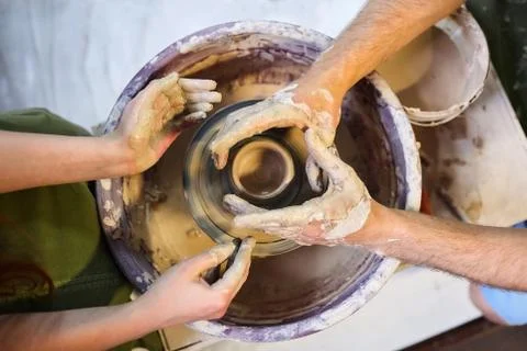 The master helps the student to make a pot of clay. Pottery wheel Stock Photos