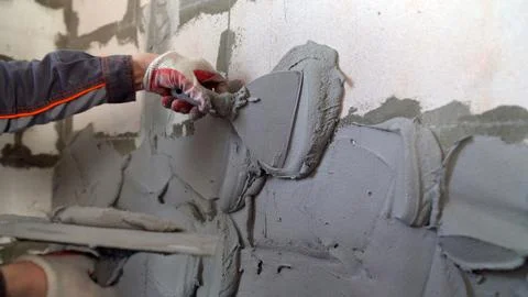 The master holds a spatula with a solution in his hand, applying plaster to.. Stock Photos