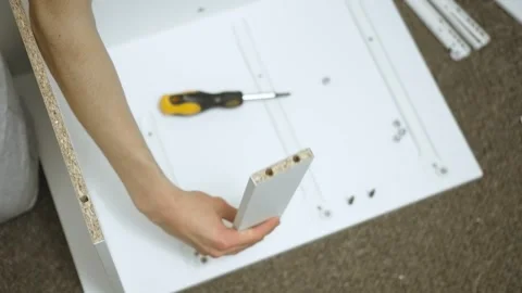 Master inspecting drawer side piece during dresser assembling Stock Footage 328370615
