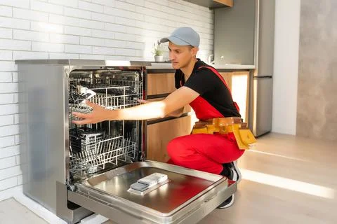 Master installing the dishwasher in a kitchen cabinet Stock Photos