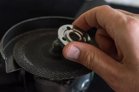 The master installs the cutting wheel in the angle grinder	 Stock Photos