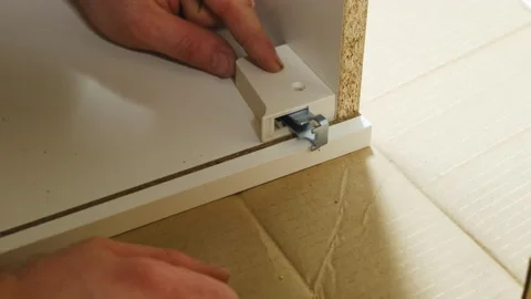 Master installs hinges for sliding drawer on wooden carcass put on floor Stock Footage 304399647