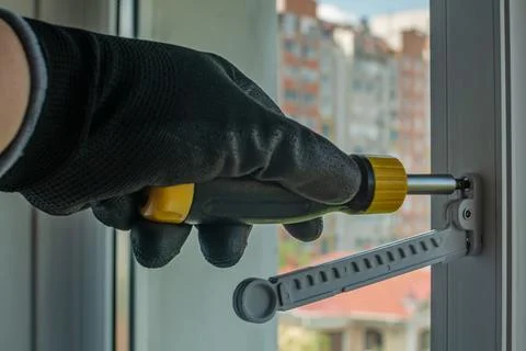 The master installs a window opening limiter on a plastic window frame. Clo.. Stock-Fotos