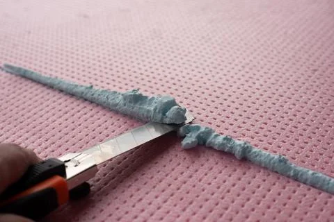 The master with a knife cuts off excess construction foam Foto stock