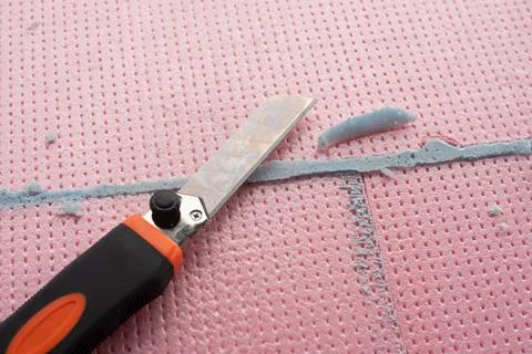 The master with a knife cuts off excess construction foam Foto stock