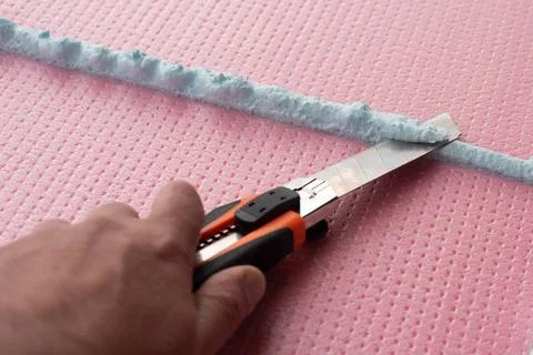 The master with a knife cuts off excess construction foam Stock Photos