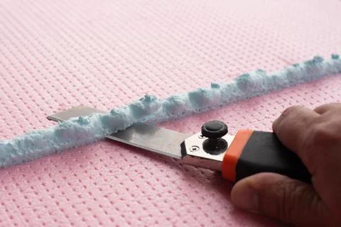 The master with a knife cuts off excess construction foam Stock Photos