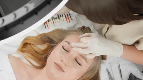 The master lashmaker in luxurious salon carefully extends eyelashes, giving Stock Footage 240287631