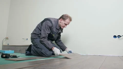 The master is laying the laminate. The man is doing the repair of the floor. Stock Footage 165431833
