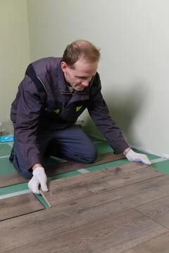 The master is laying the laminate. The man is doing the repair of the floor. Stockfoto's