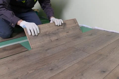 The master is laying the laminate. The man is doing the repair of the floor. Stock Photos