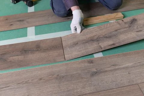 The master is laying the laminate. The man is doing the repair of the floor. Фото