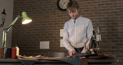 Master of the leather examines leather, rolls roll of genuine black leather Stock Footage 129566073