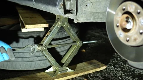 The master lifts a car with a mechanical jack with a hook. Home self-repair of t Stock Footage 320128029