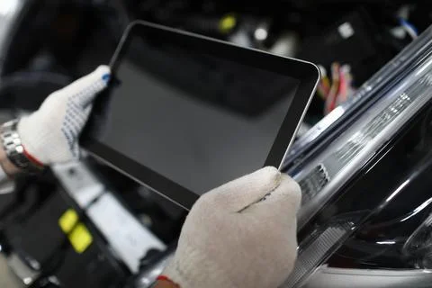 Master locksmith holds tablet open car hood Stock Photos