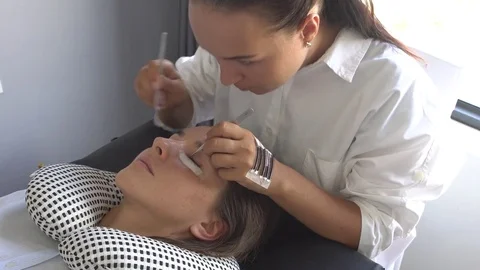Master make lashes holding pair of tweezers. Eyelash extension in beauty studio. Stock Footage 75709073