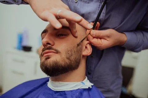 Master makes beards correction in barbershop salon. Close up photo. Stock Photos